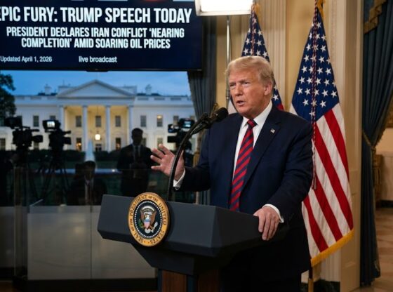President Donald Trump speaking at a White House podium with a digital screen in the background displaying the headline "EPIC FURY: TRUMP SPEECH TODAY" and news about soaring oil prices.
